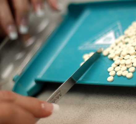 Close up view of small round pills on a tray being counted out.